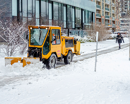 Scarborough Snow Removal - snow plow clearing street from road and walkway in front of pedestrian